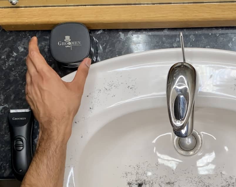 hand picking up GroomenUK Vacgroom cleaner by sink 